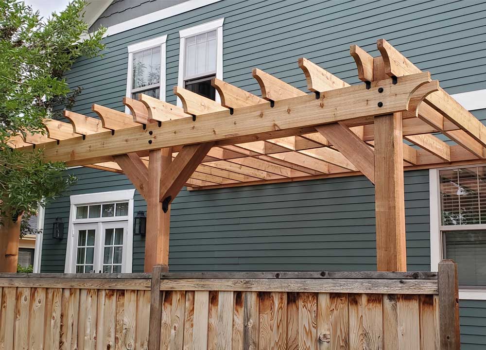 A backyard garden featuring a traditional wooden pergola with intricate supports, enhancing the outdoor space.