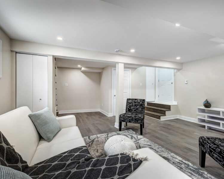 A comfortable basement living area with soft furnishings, modern decor, and a staircase leading to the upper floors, providing a warm and inviting family space.