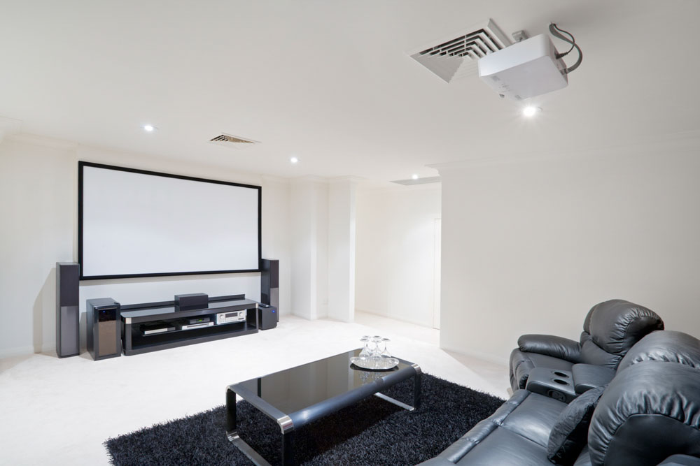 A sleek home theater room with black leather seating, a large projection screen, and sophisticated audio equipment, ideal for family movie nights.